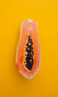 a half of a papaya on a yellow background