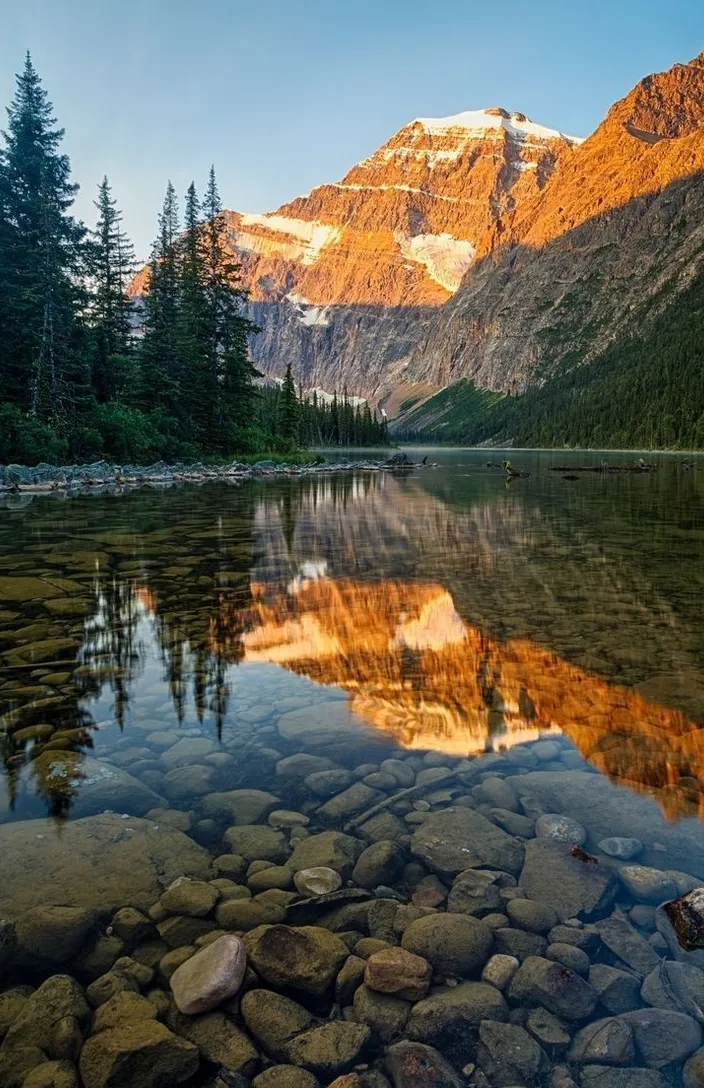 a lake surrounded by mountains with rocks in the foreground