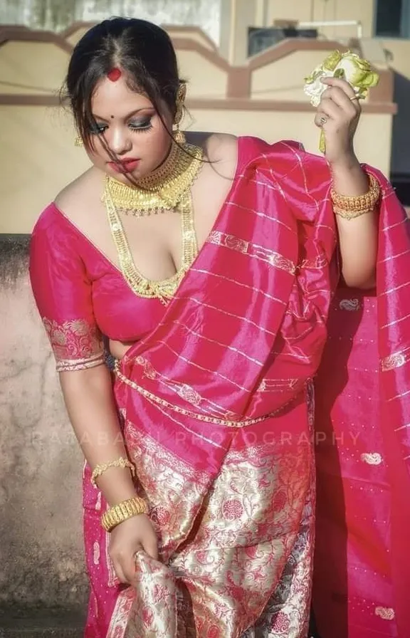 a woman in a pink sari holding a piece of food