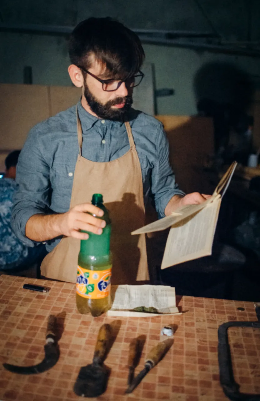 a man in an apron holding a bottle of beer