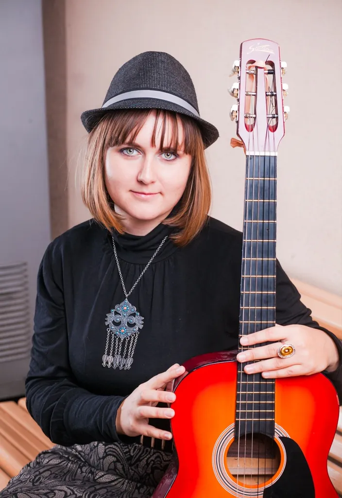 Woman playing a guitar in a vintage park surrounded by autumn leaves