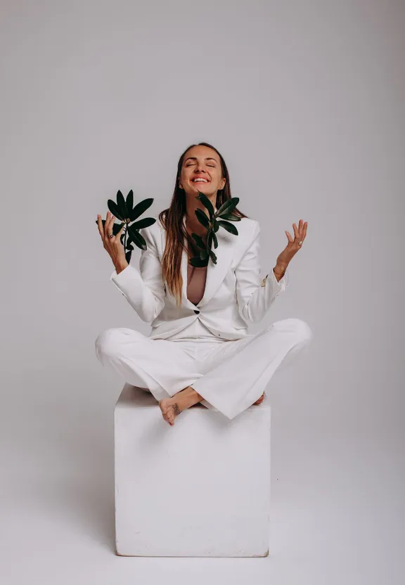 a woman in a white suit sitting on a white block