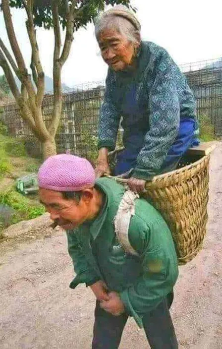 an Yang man carrying his mother in the a basket on her back