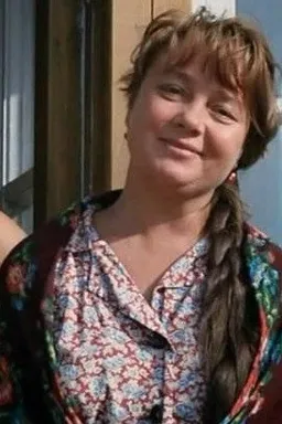 a woman with long braids standing in front of a window