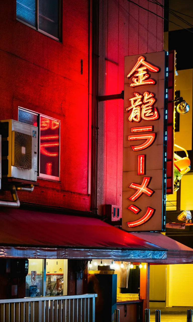 a neon sign is lit up on the side of a building  in Oasaka Japan