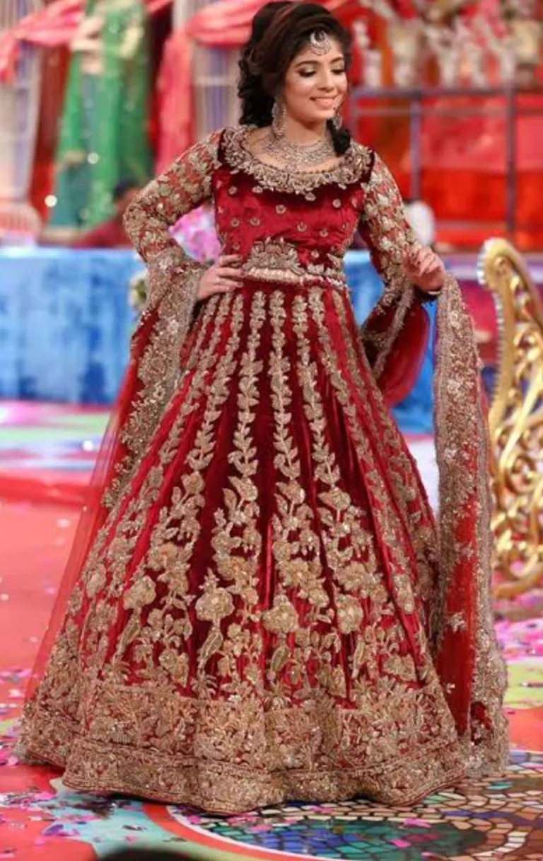 A Woman in a red and gold wedding gown standing in front of a grand, snowy palace