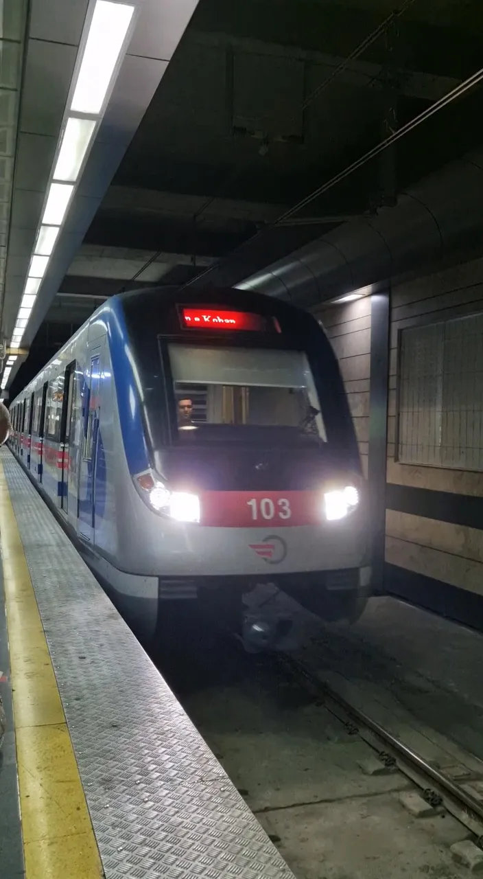 a train pulling into a train station next to a platform colorful monster with red eyes