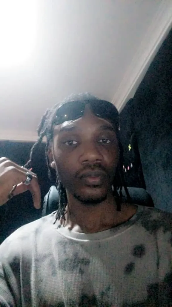 a man with dreadlocks getting his hair styled, his face transforms to Nigerian musician Wizkid's face over 2 seconds then transforms back over 2 seconds