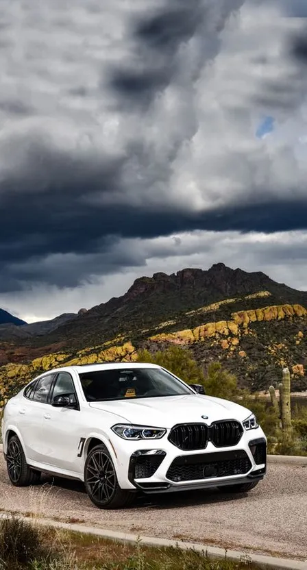 a white car driving down a road under a cloudy sky