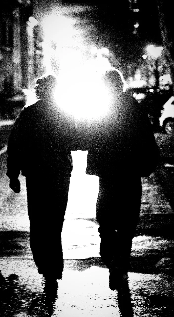 two people walking down a street at night