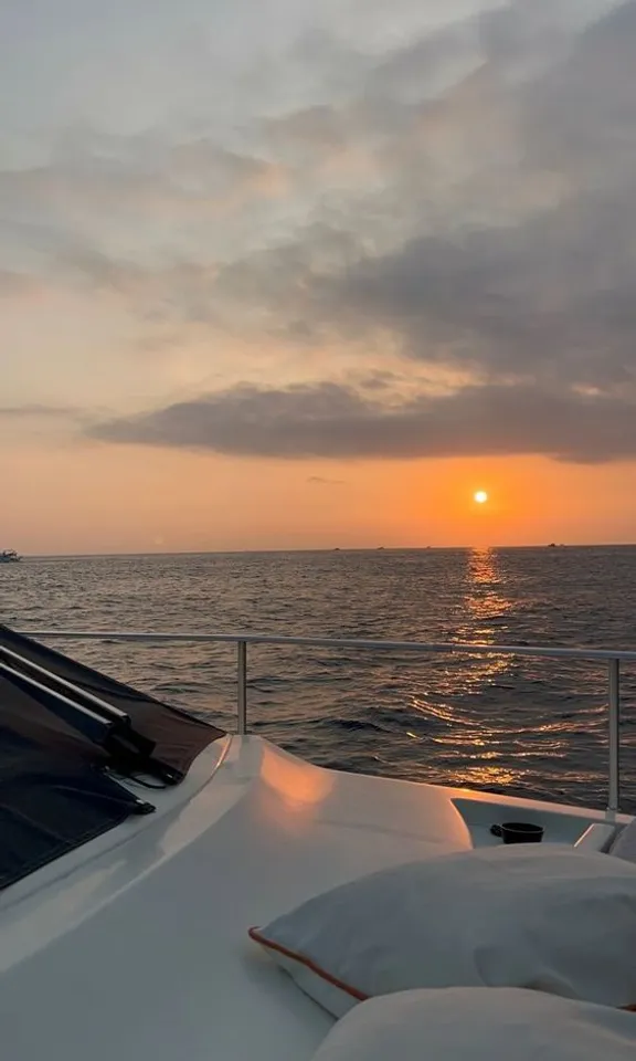 the sun is setting over the ocean on a boat