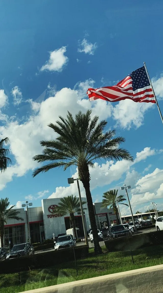 an american flag flying in front of a car dealership