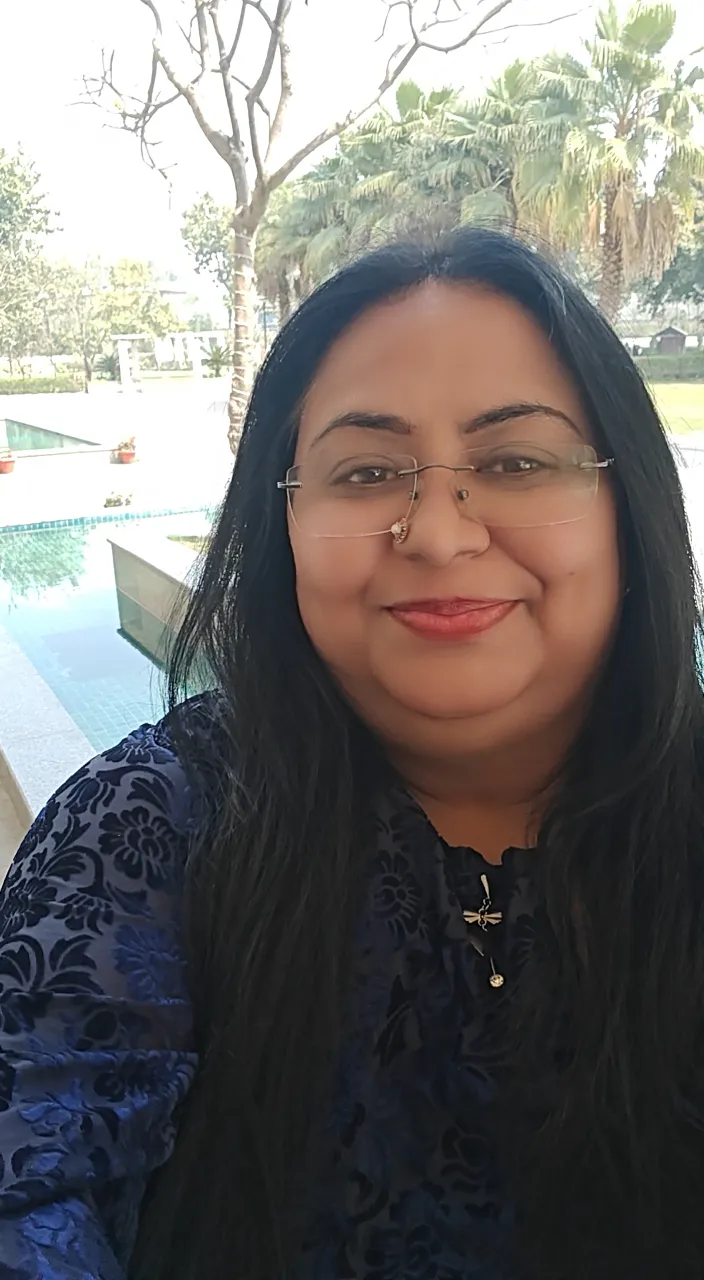 a woman wearing glasses sitting next to a swimming pool