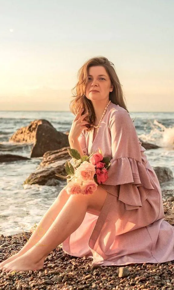 a woman sitting on a beach next to the ocean