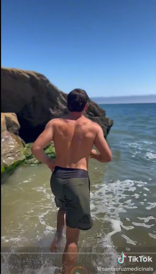 a man walking into the ocean with his back to the camera