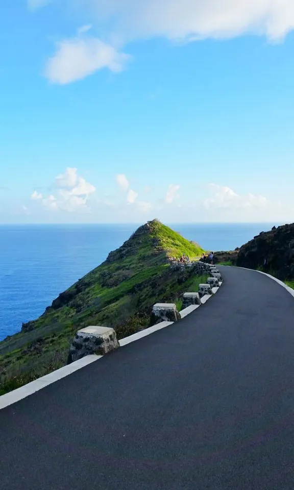 a curved road near the ocean on a sunny day