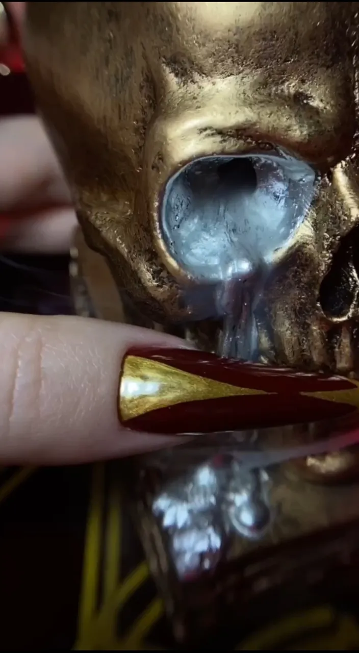 a gold skull ring with a red and gold band