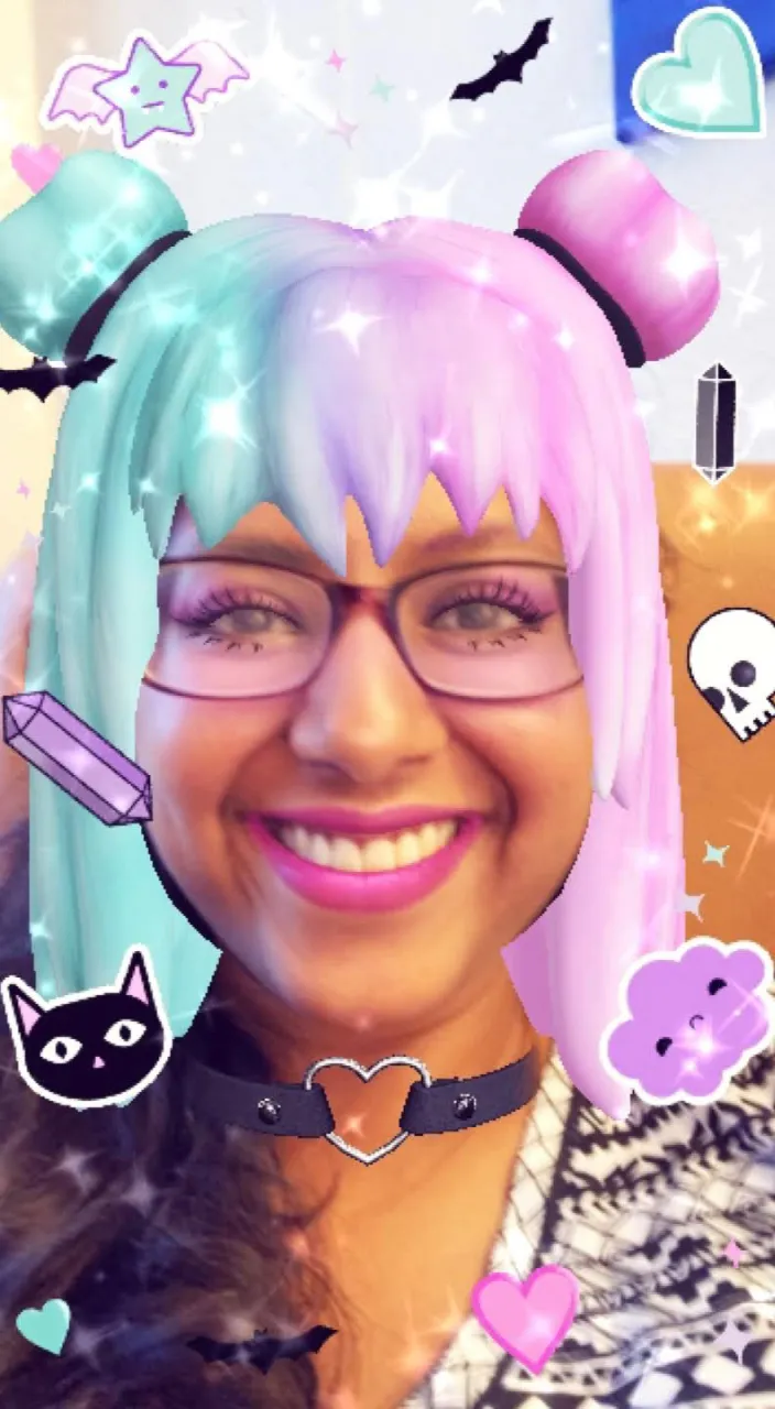 a cute woman with pastel hair and glasses smiling at the camera