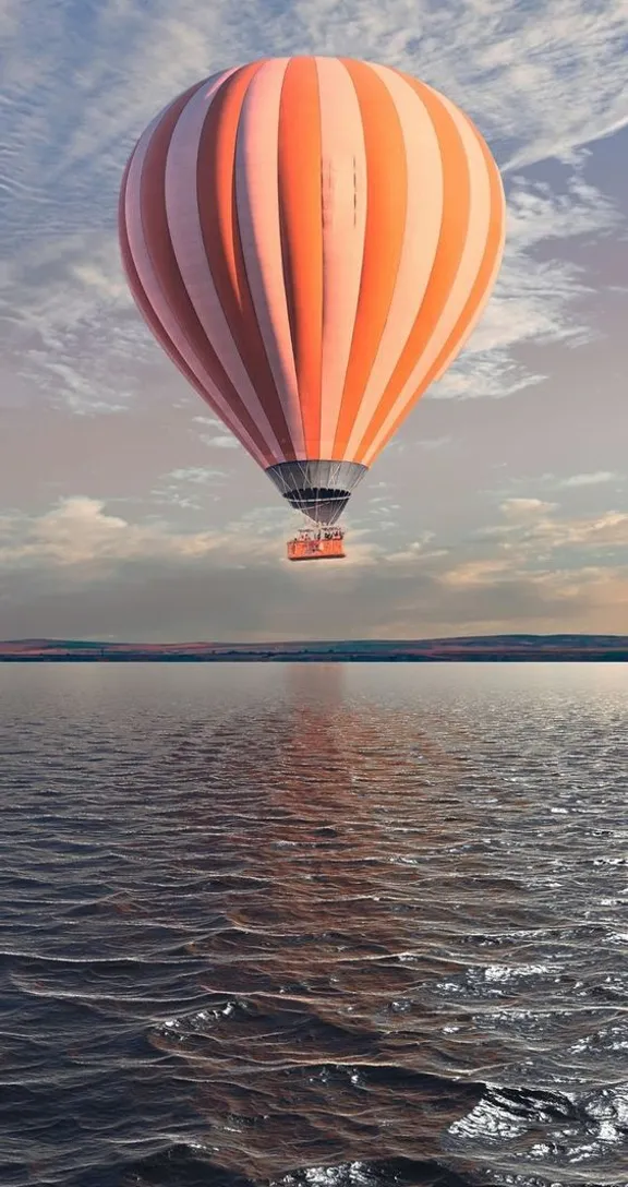 a hot air balloon flying over the ocean