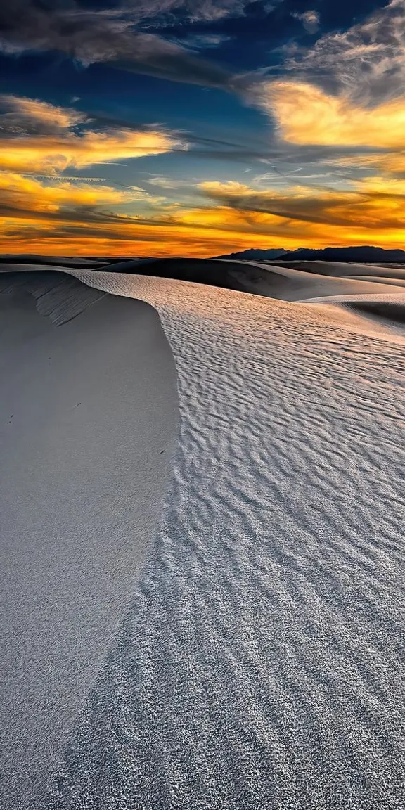 the sun is setting over the sand dunes