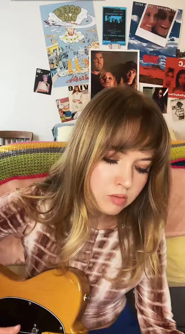 a girl playing a guitar in her bedroom