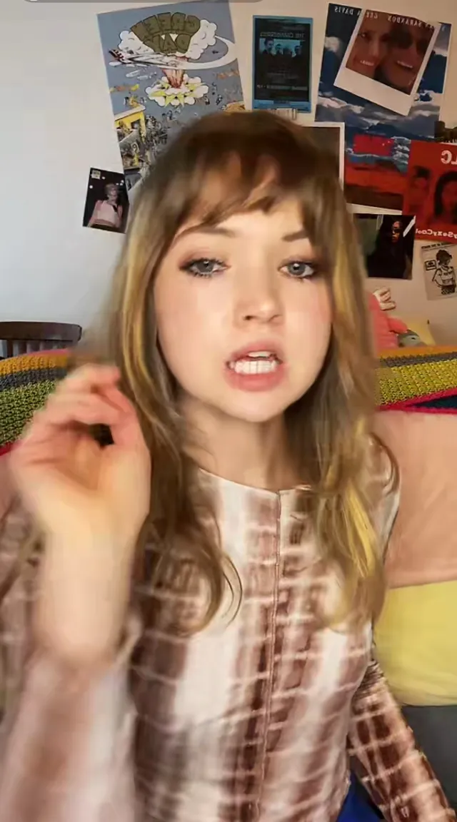 a young girl making a funny face while sitting on a bed