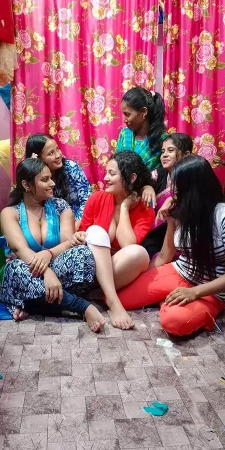 a group of women sitting on the floor in front of a pink curtain