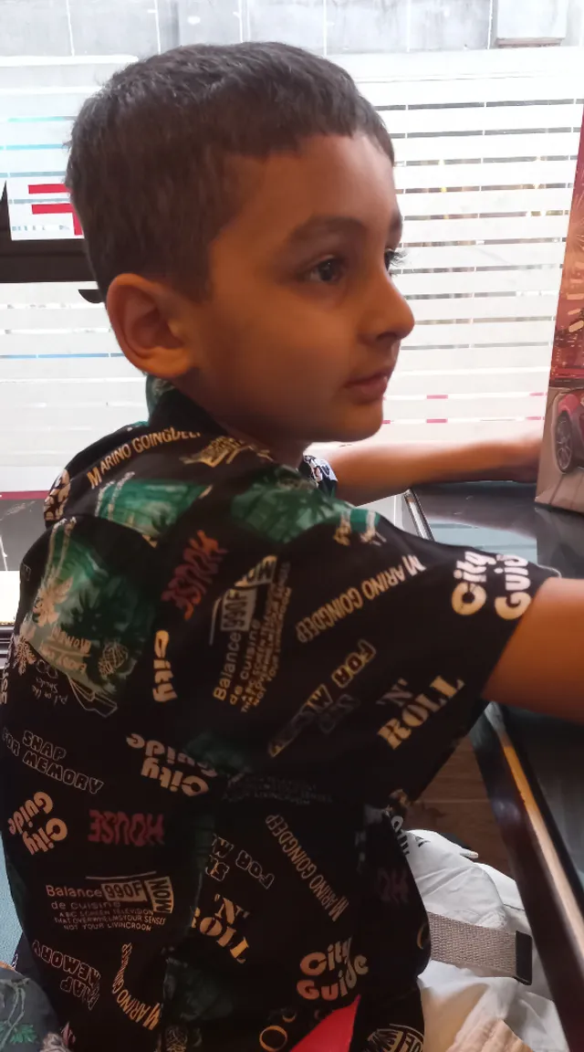 a young boy sitting at a table with a pizza